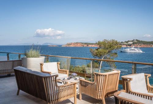 a balcony with chairs and a table and a boat at Four Seasons Astir Palace Hotel Athens in Athens