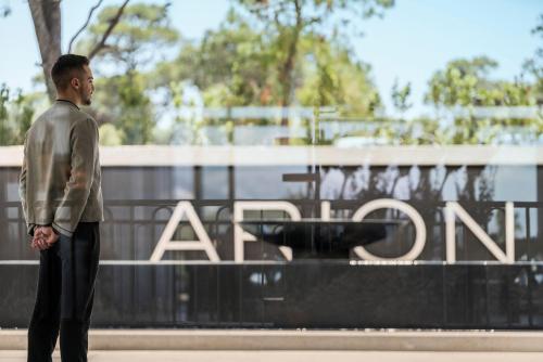 a man standing in front of a fountain in front of a sign at Four Seasons Astir Palace Hotel Athens in Athens