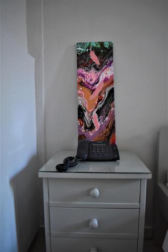 a table with a remote control on top of a dresser at Aphrodite Art Hotel Aegina in Egina