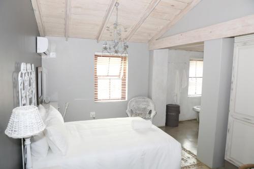 a white bedroom with a bed and a chandelier at Angel Oak guesthouse in Brits