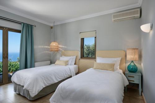 two beds in a room with a window at Artblue Villas in Tsoukaladhes