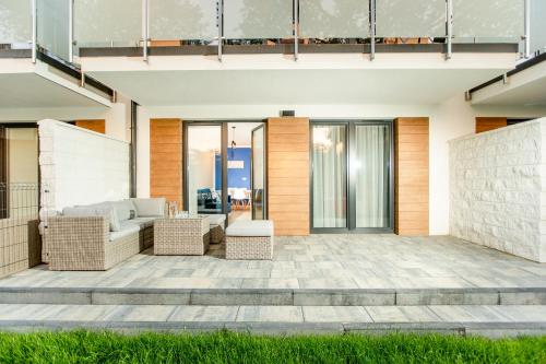 an outdoor patio with wicker furniture and glass doors at Apartamenty Sun Seasons 24 - Posesja Bałtycka in Grzybowo