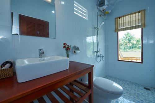 uma casa de banho com um lavatório, um WC e uma janela. em Tra Vinh Lodge em Nguyệt Hạng