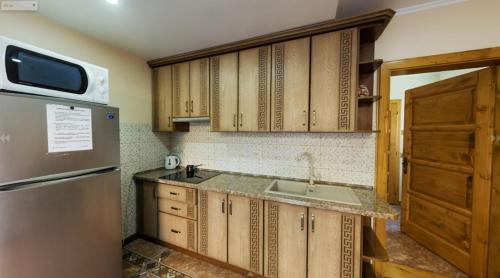 a kitchen with a refrigerator, stove, microwave and sink at Mini hotel Solnce Karpat in Polyana