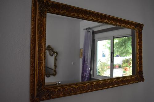 an ornate mirror on a wall with a window at Aphrodite Art Hotel Aegina in Egina