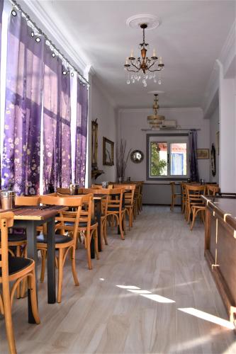 a restaurant with wooden tables and chairs and a chandelier at Aphrodite Art Hotel Aegina in Egina