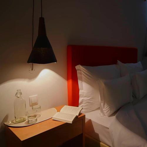 a bed with a table with a bottle and a book at Hotel da Fábrica in Manteigas