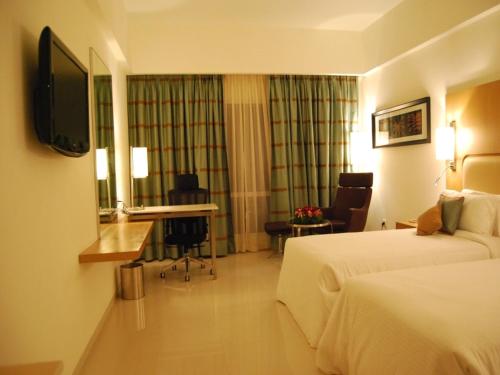 a hotel room with a bed and a desk at Royal Park Kakinada in Kākināda