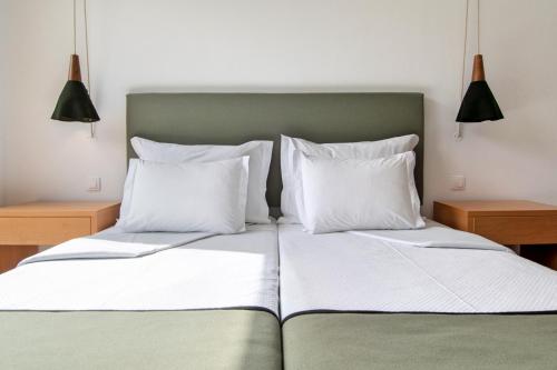 a bed with two white pillows and two lamps at Hotel da Fábrica in Manteigas