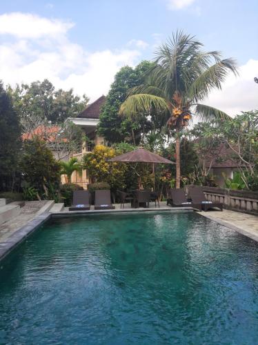 a swimming pool in front of a house at Kartika Bungalows in Ubud