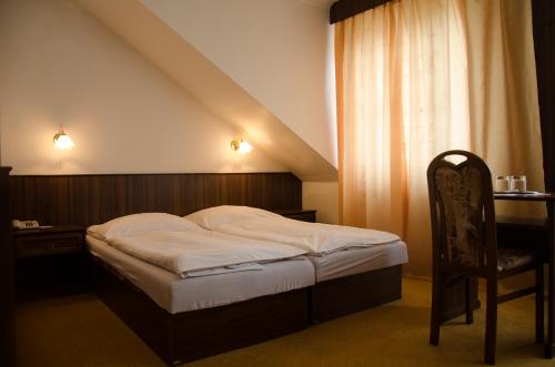 a bedroom with a bed and a desk and a chair at Penzion Pomnenka in Luhačovice