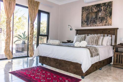 a bedroom with a large bed and a large window at Mawusi Bush Lodge in Hoedspruit