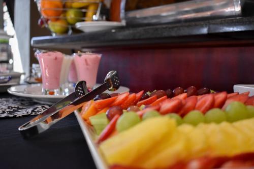 a tray of fruit on a buffet table with scissors at Waterfalls Boutique Hotel in Pretoria
