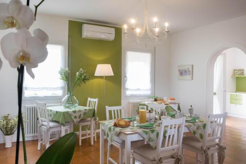 un comedor con paredes verdes, mesas y sillas blancas en La Casa di Amedeo en Piombino Dese