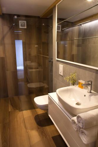 a bathroom with a sink and a shower and a toilet at Pensiunea Atra Doftana in Teşila