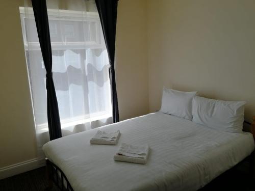 a bed with two towels on it with a window at Daisy Hotel in London