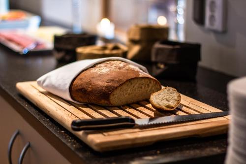 a loaf of bread on a cutting board with a knife at Hotel Hehrne Kök & Konferens in Vänersborg