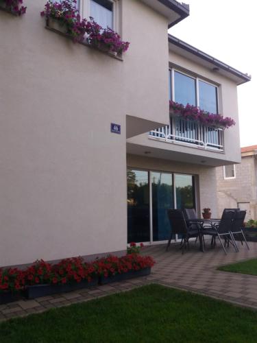 a white house with a patio with chairs and flowers at Pansion Ljubica in Međugorje