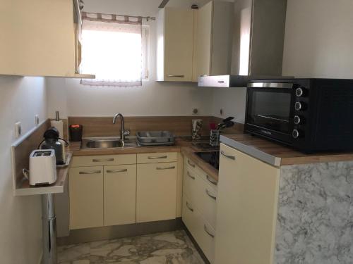 une petite cuisine avec un micro-ondes et un évier dans l'établissement T2 DE 40 M2 EN REZ DE JARDIN Avec parking CARNON PLAGE, à Mauguio