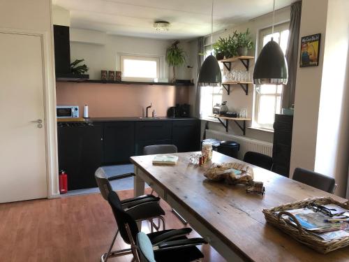 a kitchen with a wooden table and chairs at Gastenverblijf Door de Poort in Tilburg