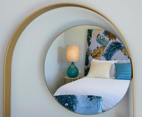 a mirror in a bedroom with a bed and a lamp at Artblue Villas in Tsoukaladhes