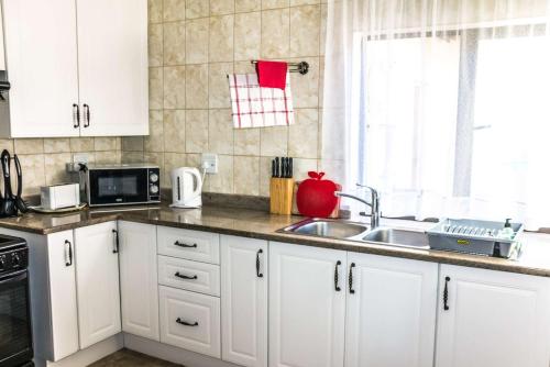 a kitchen with white cabinets and a sink at Mawusi Bush Lodge in Hoedspruit