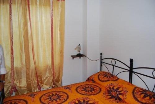 a bed with an orange bedspread with a bird on a shelf at Villa Axa in Casal Palocco