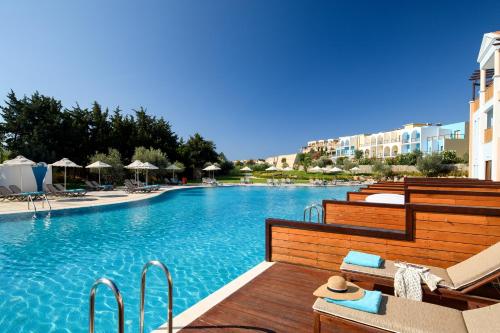 a swimming pool with chairs and umbrellas at a resort at Lindos Imperial Resort & Spa in Kiotari
