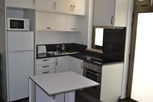 a kitchen with white cabinets and a white table in it at Casa Madalena in Barão de São João