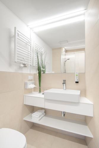 a white bathroom with a sink and a mirror at myNext - Hotel Leo in Vienna
