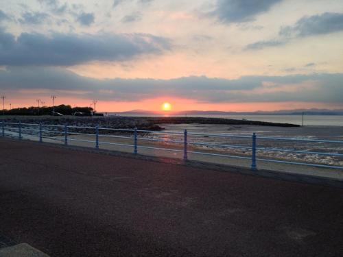 a sunset over a beach with the ocean and a fence at The Crown Hotel in Morecambe
