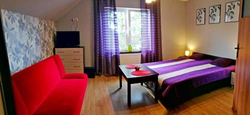 a bedroom with a purple bed and a red chair at Ranczo u Stefana in Ustronie Morskie