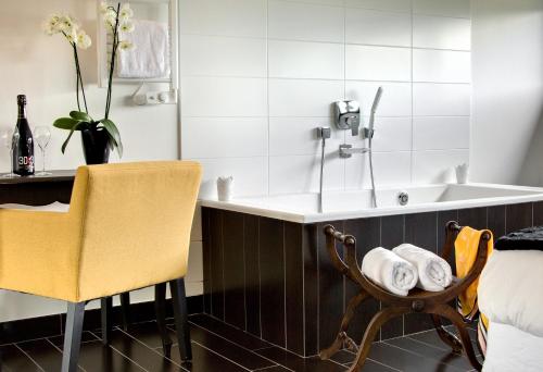 La salle de bains est pourvue d'un lavabo et d'une chaise à côté d'un lit. dans l'établissement Aux Chambres d'à Coté, à Courcelles-Sapicourt