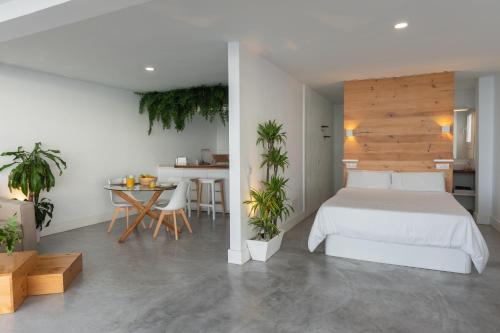 um quarto com uma cama branca e uma mesa com plantas em Waves Nest - Bajamar em Bajamar