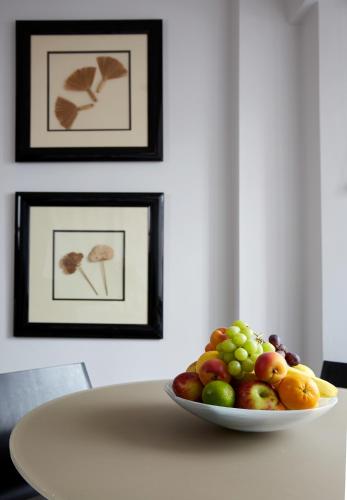 a plate of fruit on a table with framed pictures at Cheval Knightsbridge in London