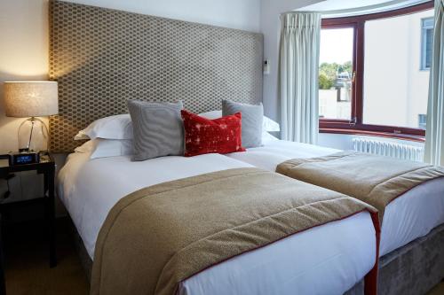 a bedroom with a large white bed with red pillows at Cheval Knightsbridge in London