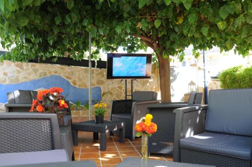 a patio with chairs and a tv under a tree at Mini Golf Apartments in Canyamel