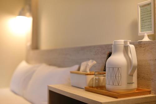 a bottle of moisturizers sitting on a table next to a bed at Cheese Cookie Homestay in Magong