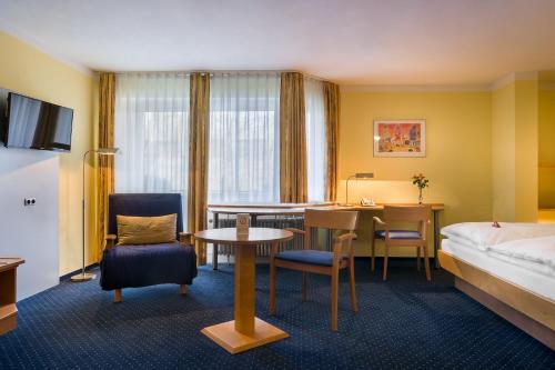カールスルーエにあるacora Karlsruhe Zentrum Living the Cityのベッド、テーブル、椅子が備わるホテルルームです。