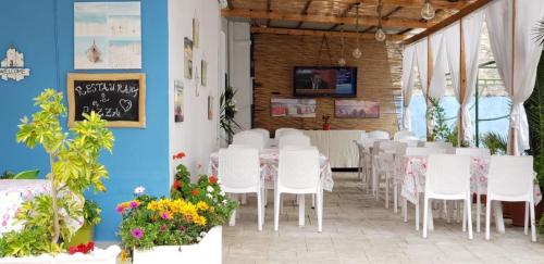 a room with tables and white chairs and flowers at The First Hotel Saranda in Sarandë