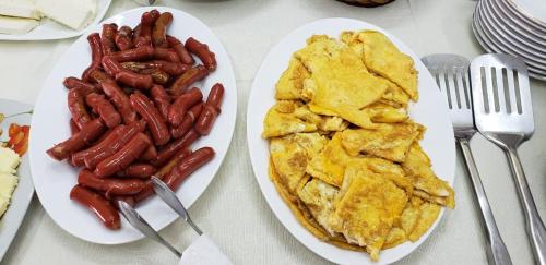 two plates of breakfast food with sausage and pancakes at The First Hotel Saranda in Sarandë