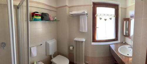 a bathroom with a toilet and a sink and a window at R.T.A. Hotel Monte Rosa in Champoluc
