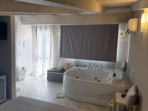 La salle de bains est pourvue d'une grande baignoire blanche et d'une fenêtre. dans l'établissement Imperatrice Livia, à Fondi