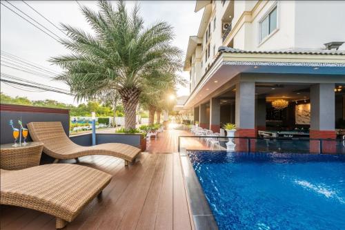 a swimming pool with wicker chairs next to a building at Napheera Royal Tel in Ban Khlong Bang Krathiam