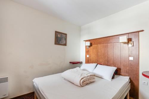 une chambre avec un lit blanc avec une tête de lit en bois dans l'établissement Residence Le Mont Soleil - maeva Home, à Plagne Villages