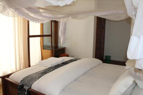 a bedroom with a bed with white sheets and a window at Villa Dahl Beach Resort in Dar es Salaam