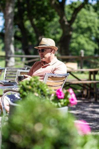 a man wearing a hat sitting on a park bench at Hotel Hehrne Kök & Konferens in Vänersborg
