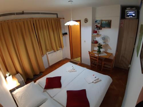 a bedroom with a white bed with red pillows on it at House Osana in Grabovac