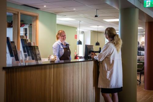 two women standing at a counter in an office at Hotel Hehrne Kök & Konferens in Vänersborg