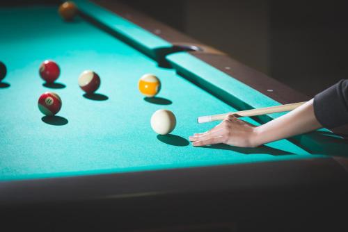 a woman playing pool with a cue and balls on a pool table at Hotel Sevtopolis Medical & SPA in Pavel Banya